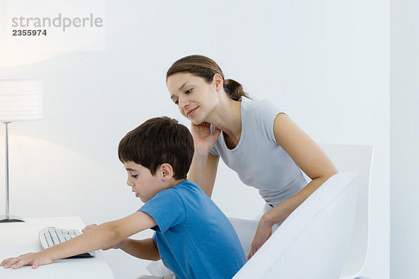 Kleiner Junge mit Computertastatur  Mutter wacht über seine Schulter