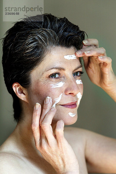 Frau über vierzig Creme auf ihrem Gesicht Umsetzung