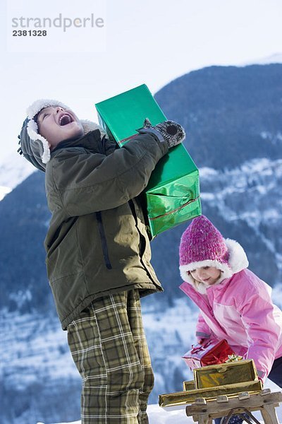 Junge und Mädchen mit Geschenken im Schnee