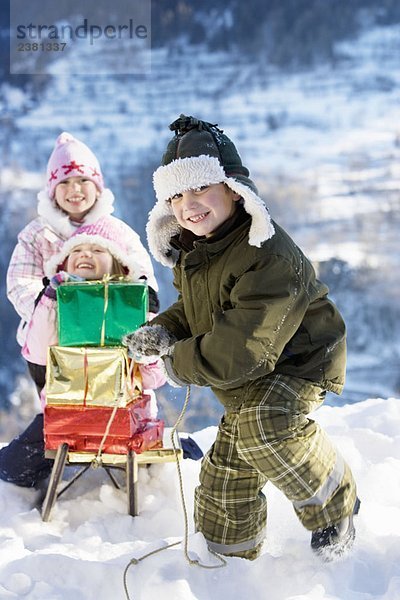 Kinder spielen im Schnee mit Geschenken