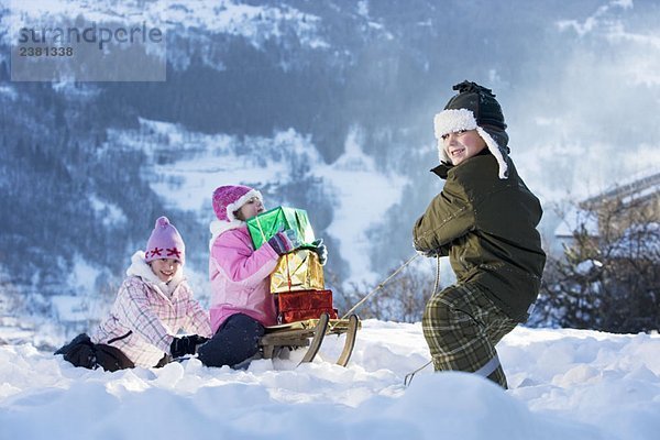 Kinder spielen im Schnee mit Geschenken