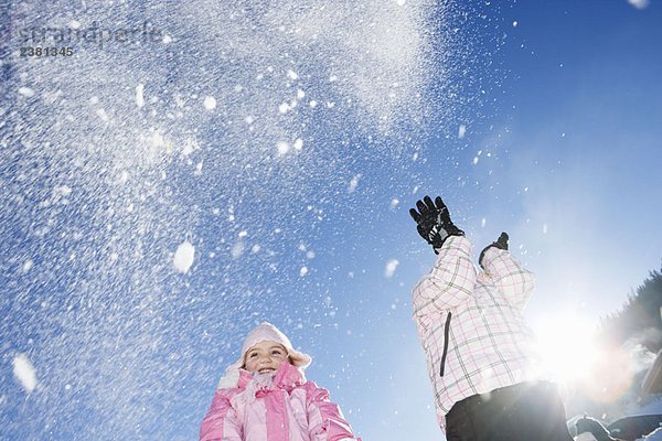 Junge Mädchen werfen Schnee in die Luft