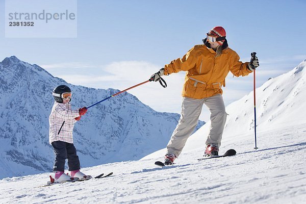 Mutter zieht Kind auf Skiern