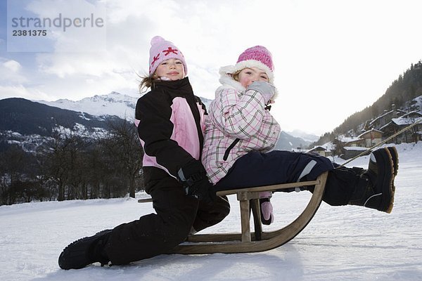 Mädchen auf Schlitten im Schnee geschleppt