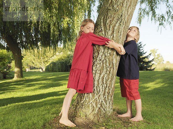 Junge und Mädchen umarmen Baum