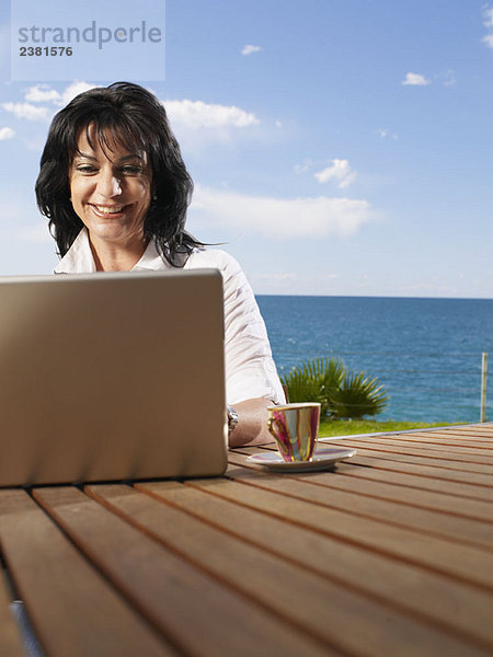 Frau auf Laptop im Freien auf dem Deck