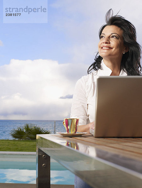 Frau auf Laptop im Freien auf dem Deck