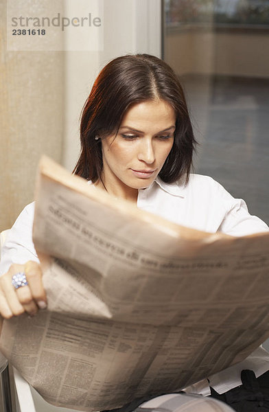 Junge Frau liest Finanzzeitung