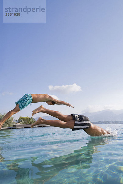 Junge Männer  die in einen Pool springen