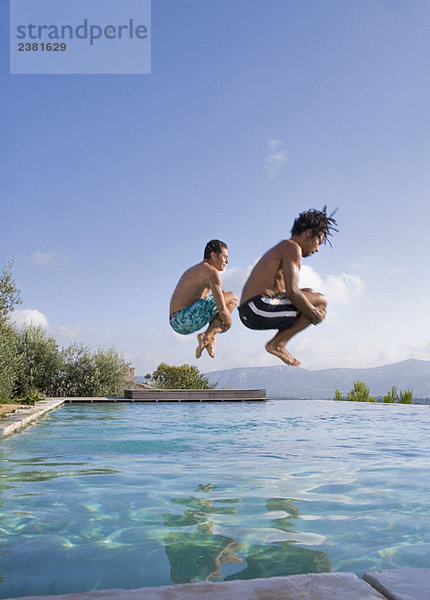 Junge Männer  die in einen Pool springen.