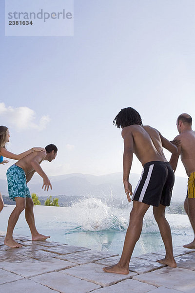 Männer und Frauen werfen einen Freund in einen Pool.