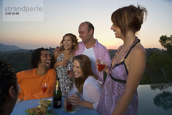 Männer und Frauen auf einer Party bei Sonnenuntergang