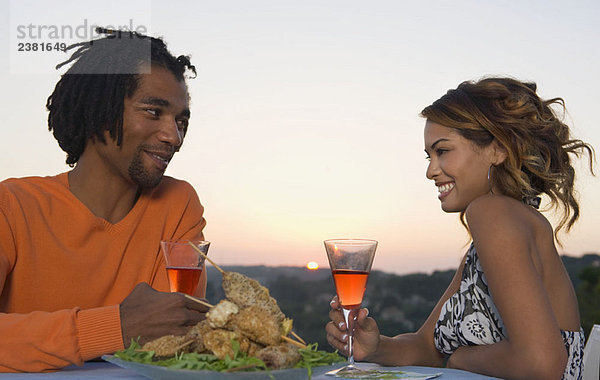 Mann und Frau beim Grillen bei Sonnenuntergang