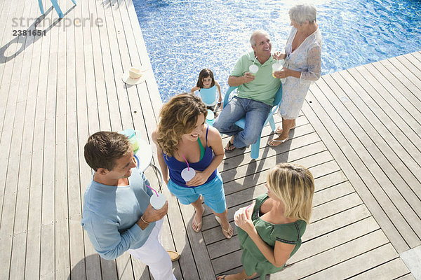 Familie auf einer Holzterrasse am Pool