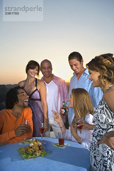 Junge Leute beim Abendessen bei Sonnenuntergang