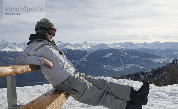 Snowboarder auf Bank sitzend