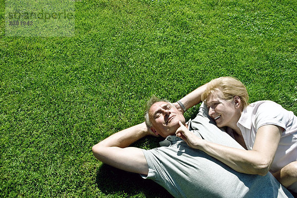 Mann und Frau liegen zusammen auf Gras.