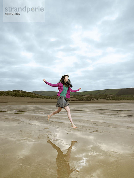 Junge Frau beim Springen am Strand