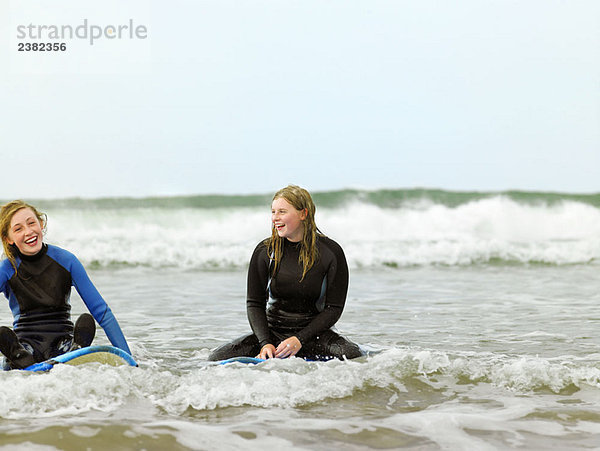 Surferinnen auf Surfbrettern sitzend