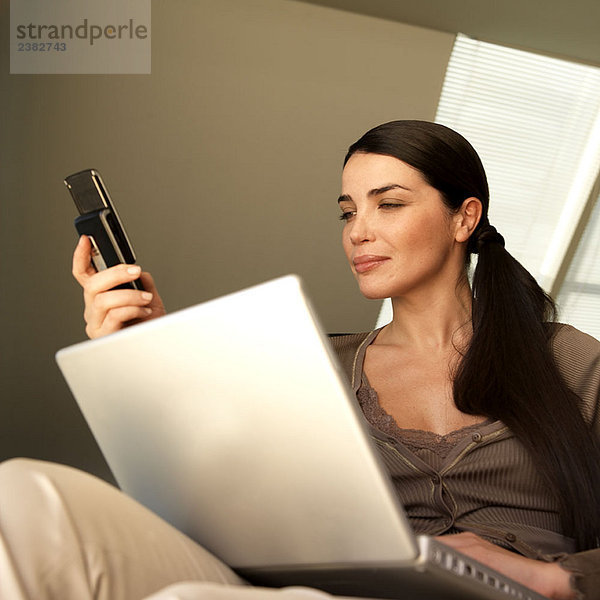 Frau mit Laptop und Telefon