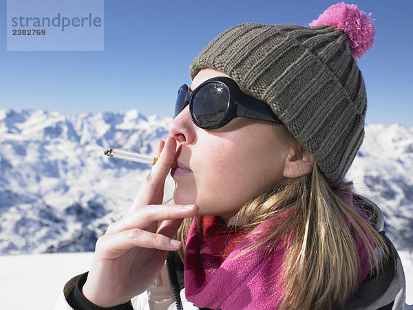 Junge Frau raucht in Schneekleidung