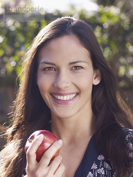 Junge Frau lächelt und hält den Apfel in der Hand