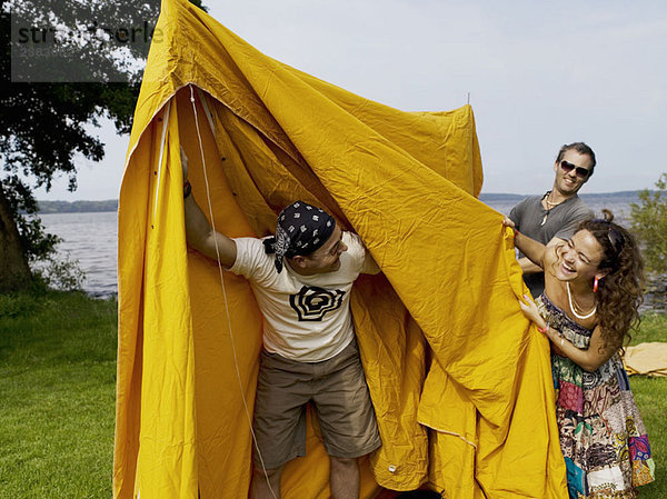 Drei Personen bauen ein Zelt auf
