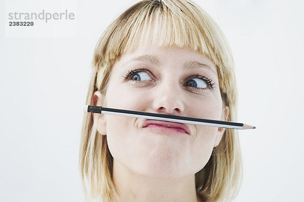 Amüsante Frau mit Bleistift über dem Mund