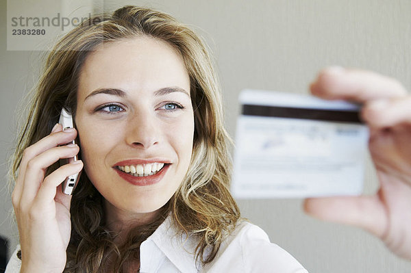 Frau am Telefon  schaut auf Kreditkarte