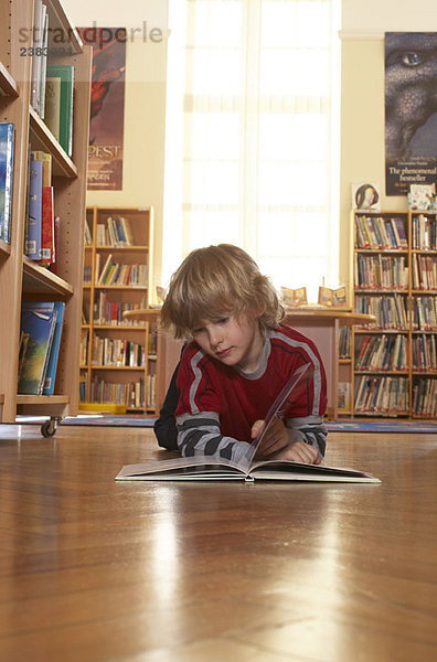 Junge liest ein Buch auf dem Boden