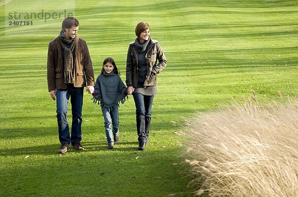 Mädchen mit ihren Eltern beim Spaziergang im Park