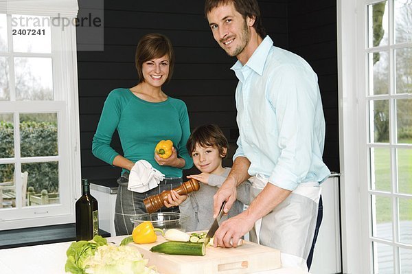 Ein erwachsener Mann und eine junge Frau  die mit ihrem Sohn Essen zubereiten.
