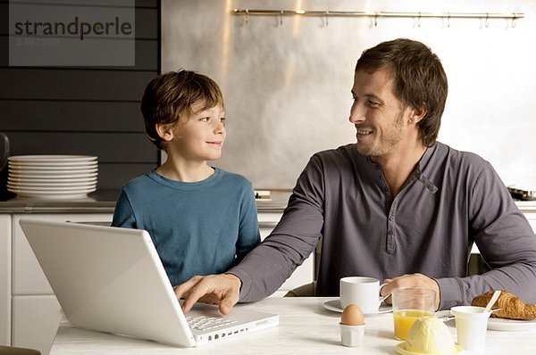 Mid Erwachsenen Mann mit einem Laptop und Blick auf seinen Sohn