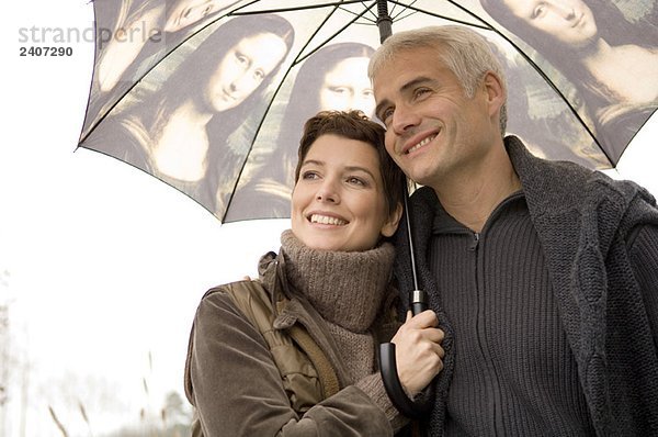 Nahaufnahme einer mittleren erwachsenen Frau und eines reifen Mannes unter einem Regenschirm