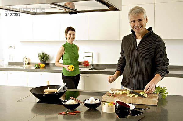 Porträt eines reifen Mannes und einer mittleren erwachsenen Frau bei der Zubereitung von Speisen in der Küche