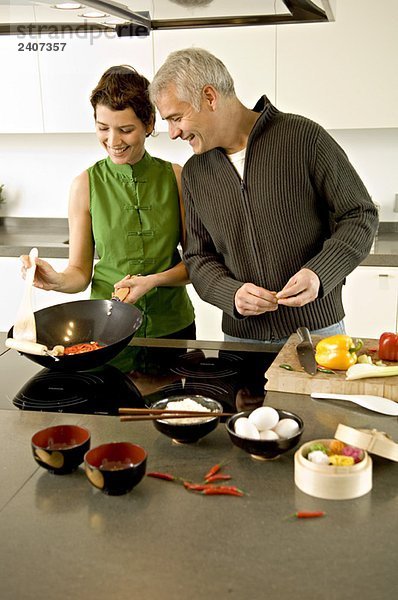 Ein reifer Mann und eine erwachsene Frau bereiten das Essen in der Küche zu.
