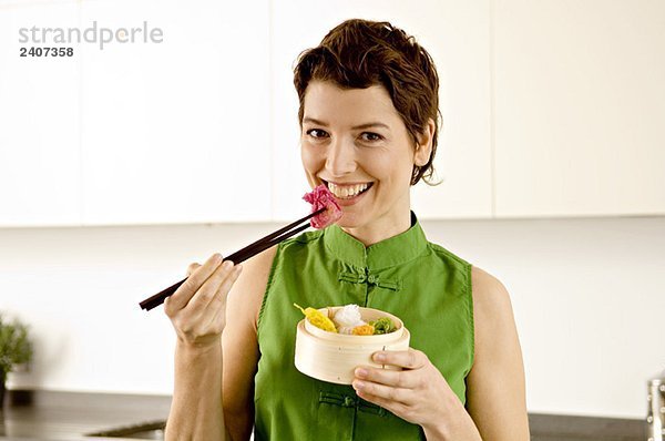 Porträt einer erwachsenen Frau beim Essen mit Essstäbchen