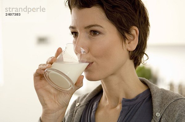 Nahaufnahme einer erwachsenen Frau  die ein Glas Milch trinkt.