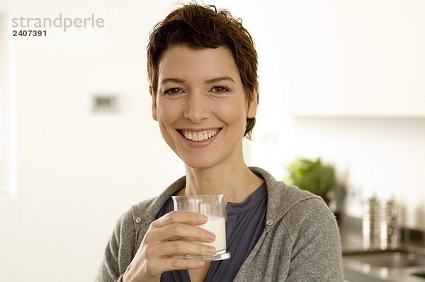 Porträt einer mittleren erwachsenen Frau mit einem Glas Milch
