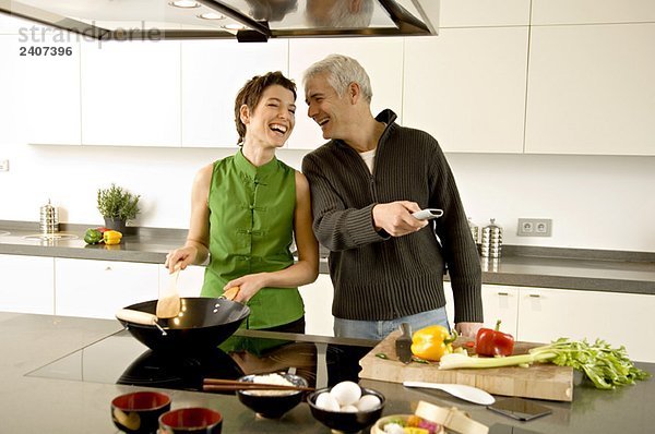 Ein reifer Mann und eine erwachsene Frau bereiten das Essen in der Küche zu.