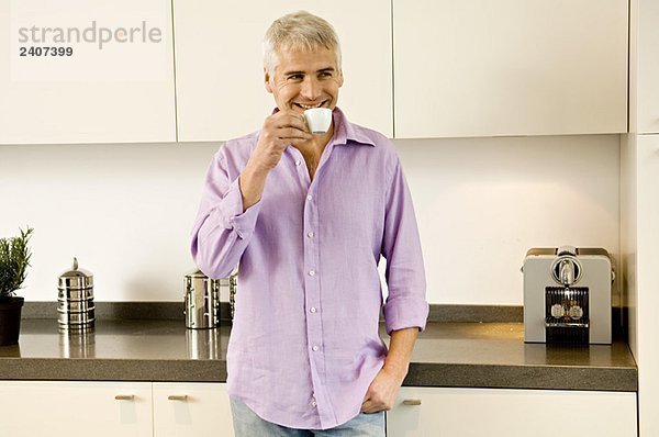 Erwachsener Mann trinkt Tee in der Küche