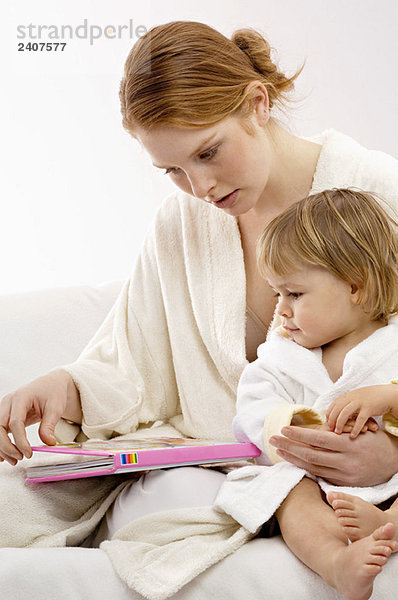 Nahaufnahme einer jungen Frau  die mit ihrem kleinen Jungen sitzt und sich ein Bilderbuch ansieht.