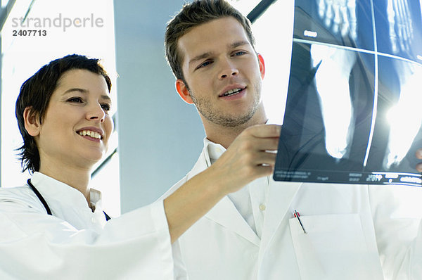 Nahaufnahme von zwei Ärzten bei der Untersuchung eines Röntgenberichtes