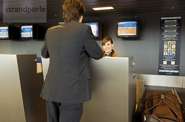 Rückansicht eines Geschäftsmannes an einem Flughafen-Check-in-Schalter