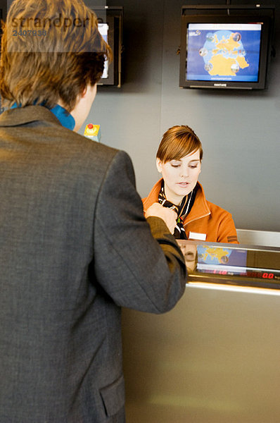 Rückansicht eines Geschäftsmannes an einem Flughafen-Check-in-Schalter