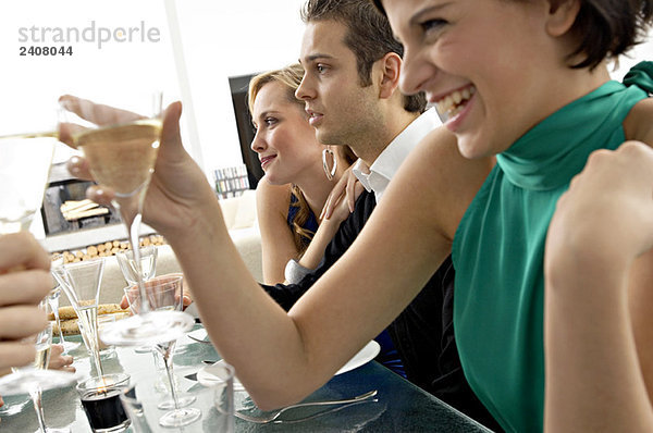 Junge Frau bei einer Dinnerparty mit Champagner anstoßen