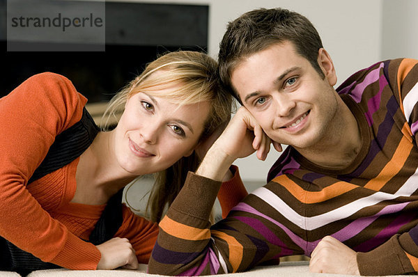 Porträt eines jungen Paares auf einer Couch liegend und lächelnd