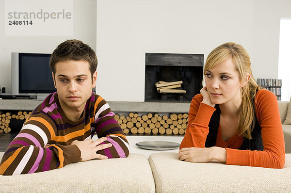 Junger Mann auf einer Couch mit einer jungen Frau  die ihn ansieht.