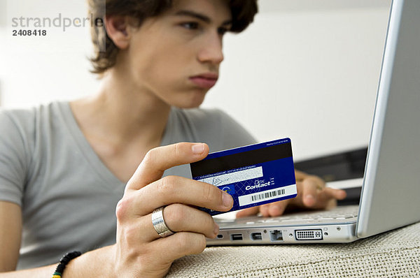 Nahaufnahme eines Teenagers mit Laptop und Kreditkarte