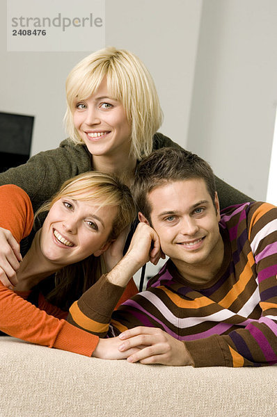 Porträt eines jungen Mannes  der mit zwei jungen Frauen lächelt